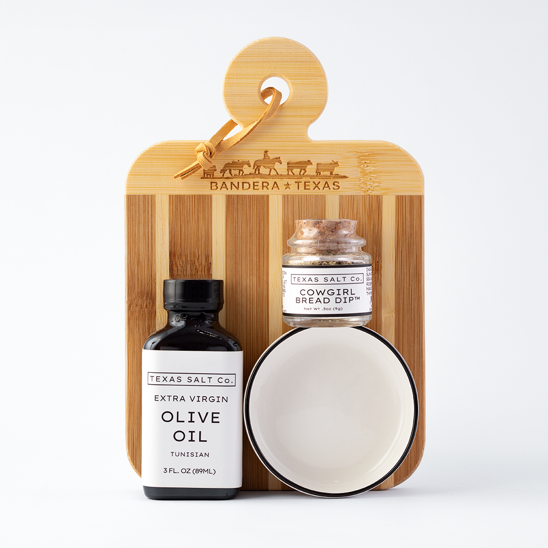 Set of Texas Salt Co products including olive oil, bread oil, and a ceramic dish on a wooden board with 'Bandera Texas' branding.
