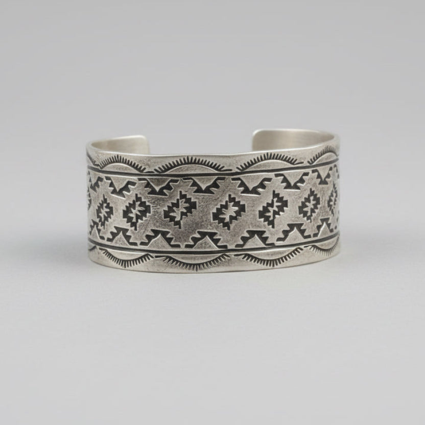 Silver bracelet with intricate patterns on a wooden surface