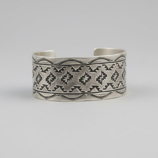 Silver bracelet with intricate patterns on a wooden surface