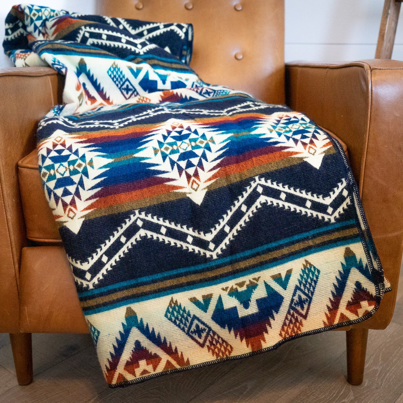 Patterned blanket draped over a brown leather chair
