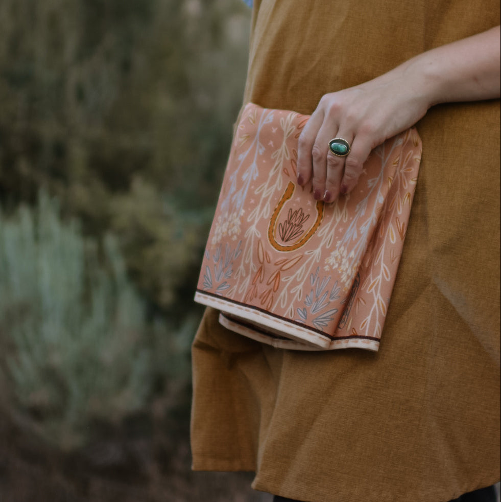 Person holding a patterned western kitchen towel with intricate design outdoors