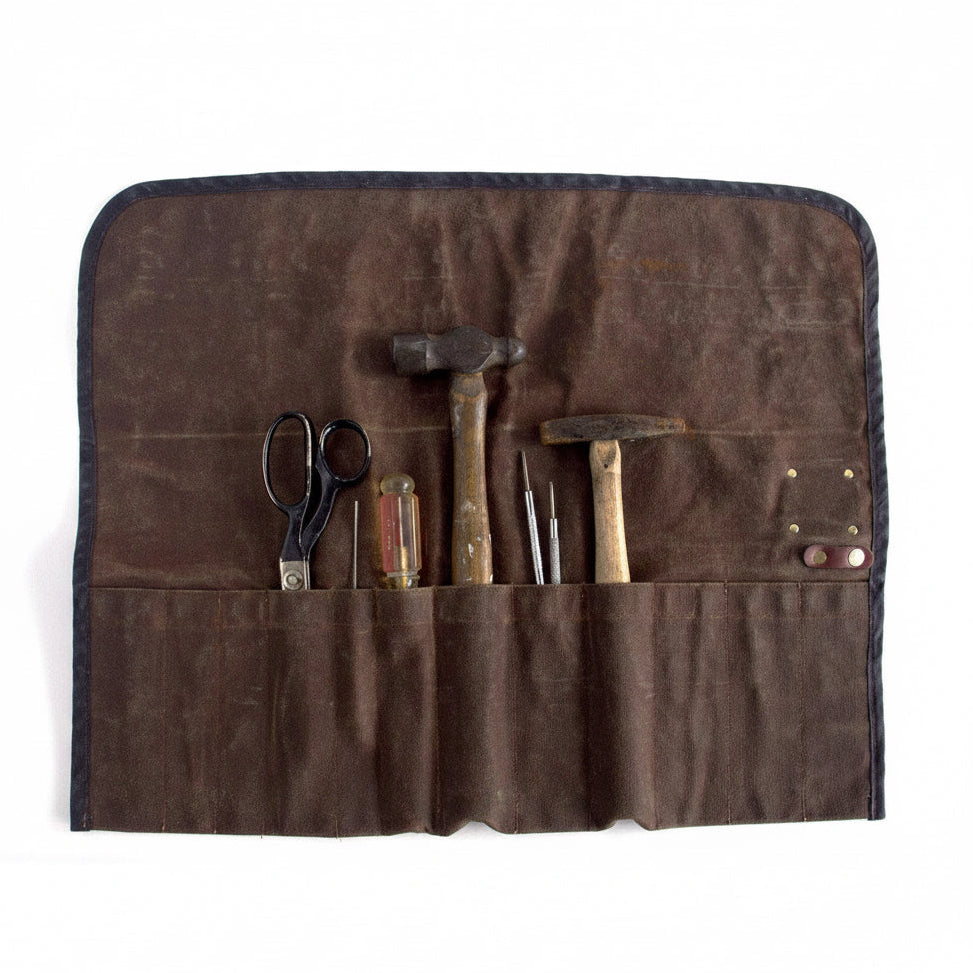 Brown tool roll with various tools on a white background