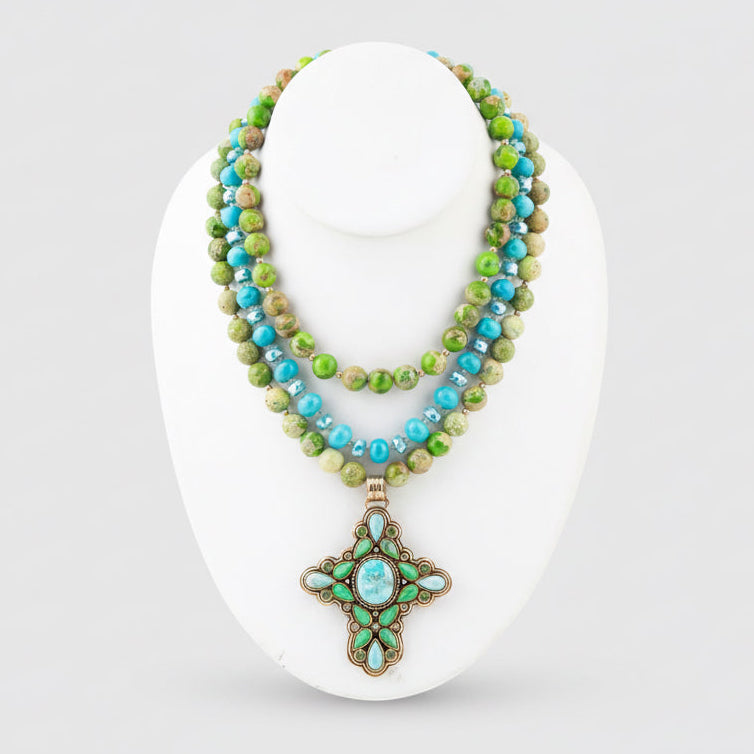 Necklace with green and blue beads on a white stand
