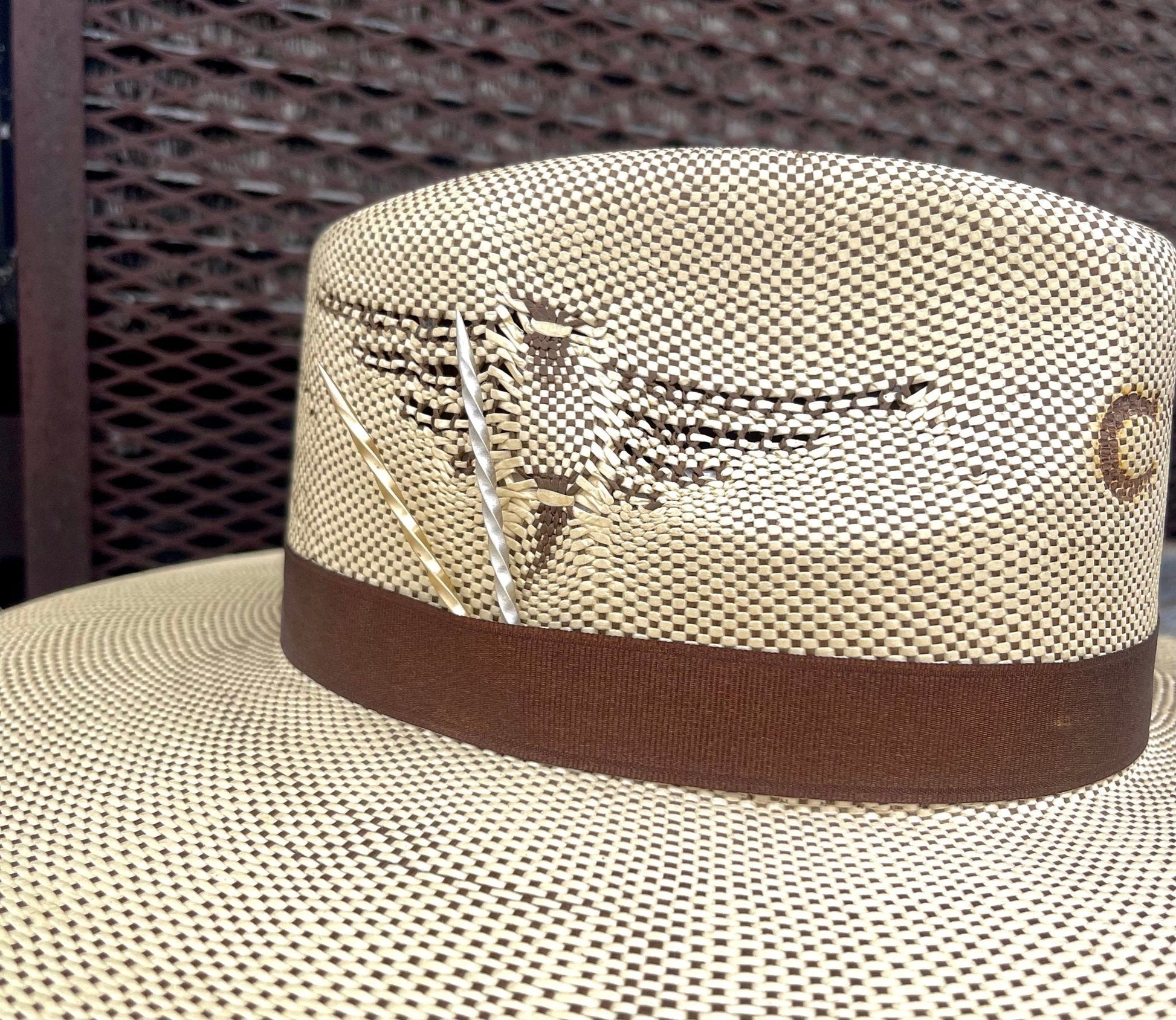 Straw cowboy hat with brown band and two cowboy toothpicks in the band.