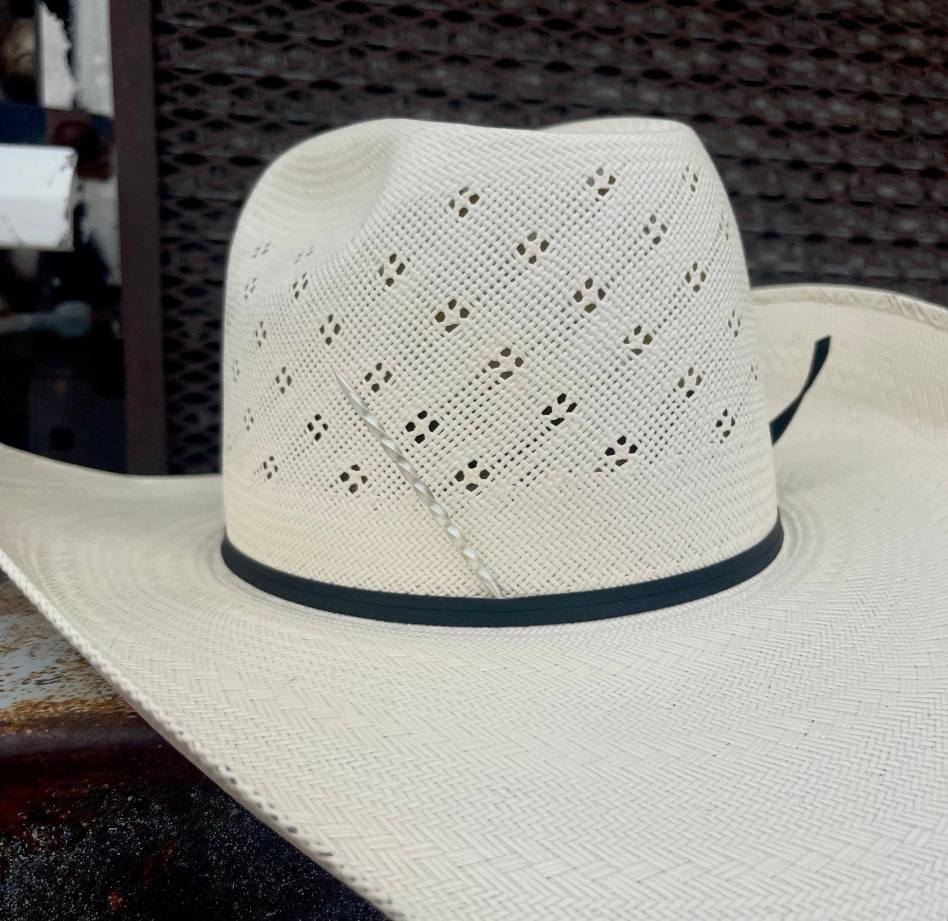 Straw hat with a black band with a silver cowboy toothpick in the band.