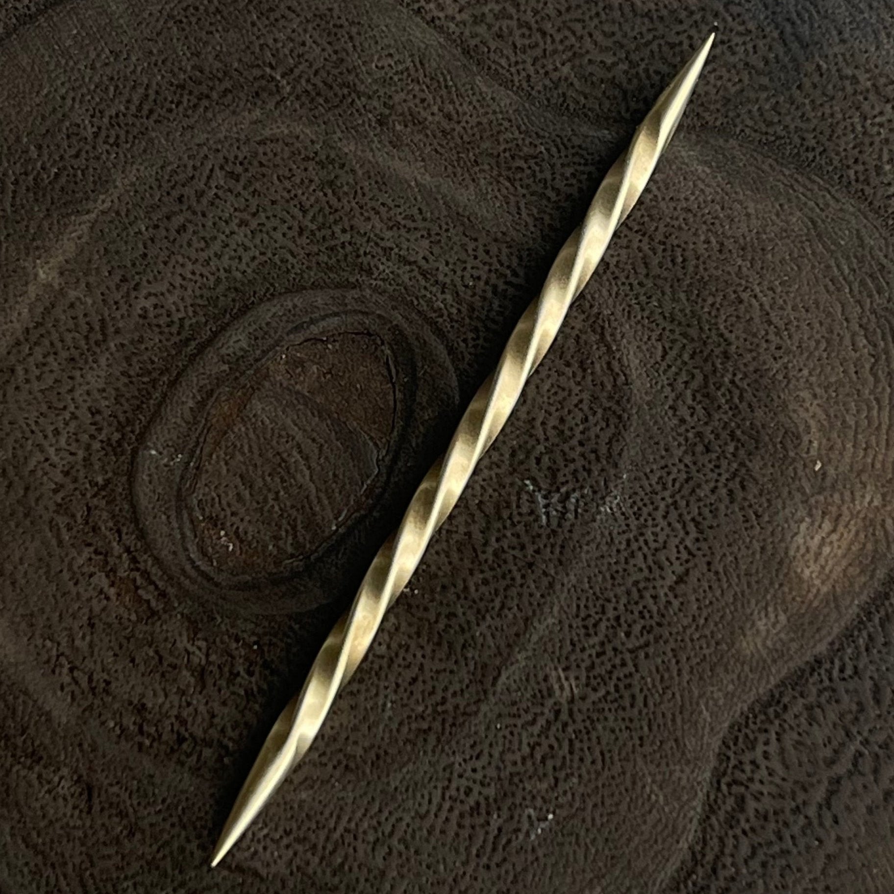Brass toothpick on a textured brown surface
