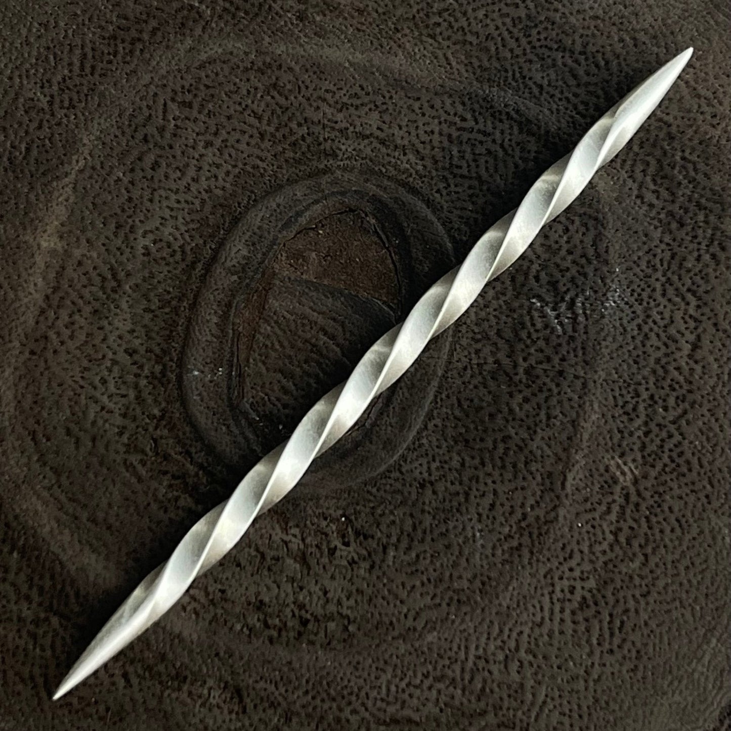 Silver toothpick on a textured brown fabric background