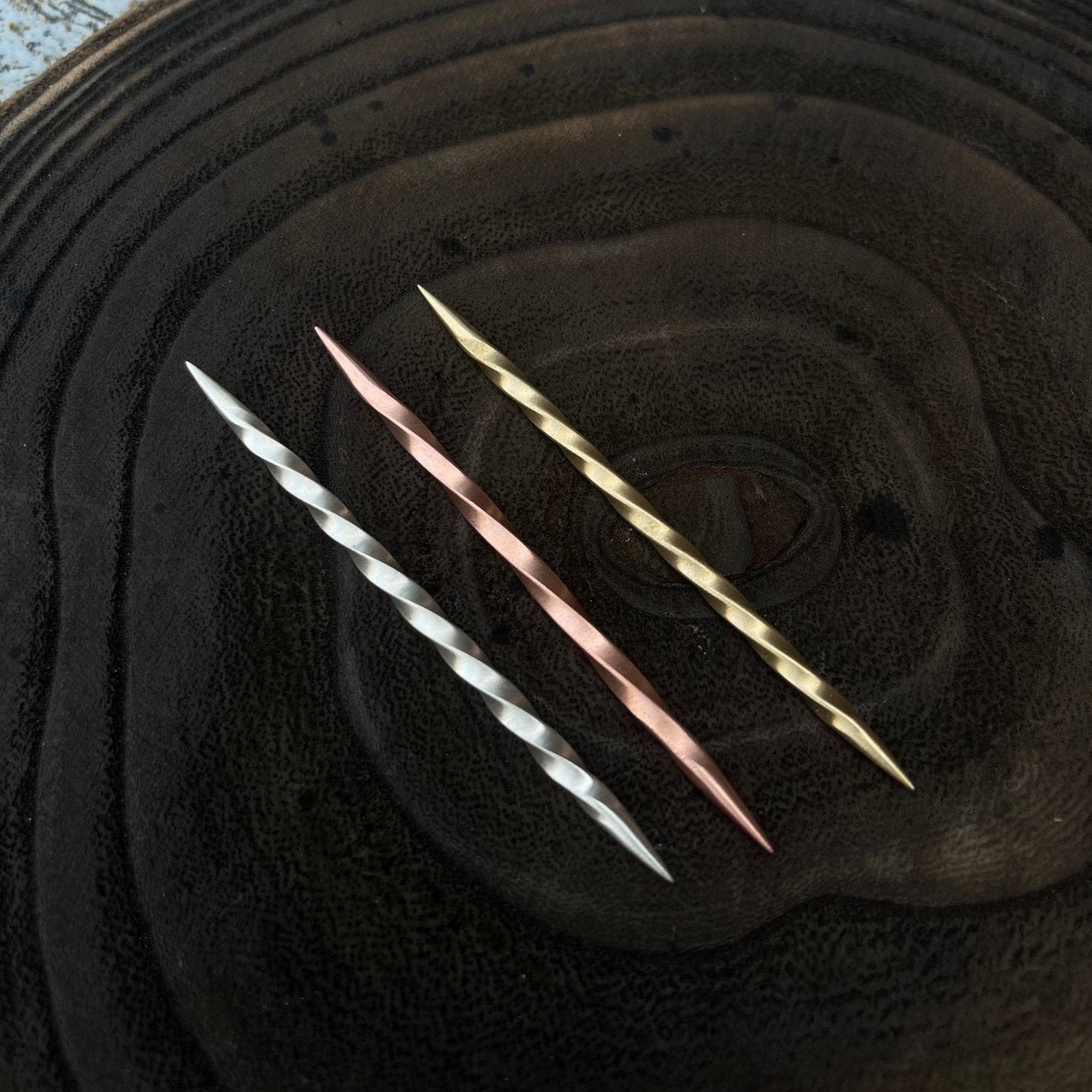 Three metallic toothpicks  on a textured black surface
