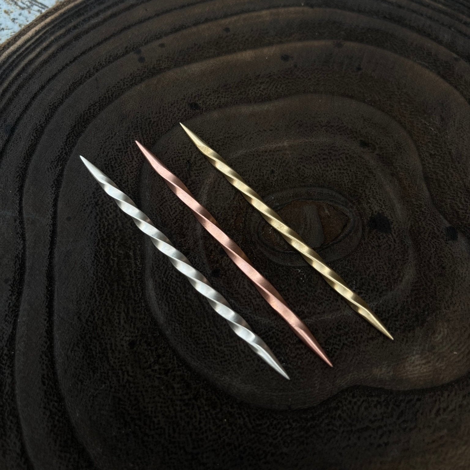 Three metallic toothpicks  on a textured black surface