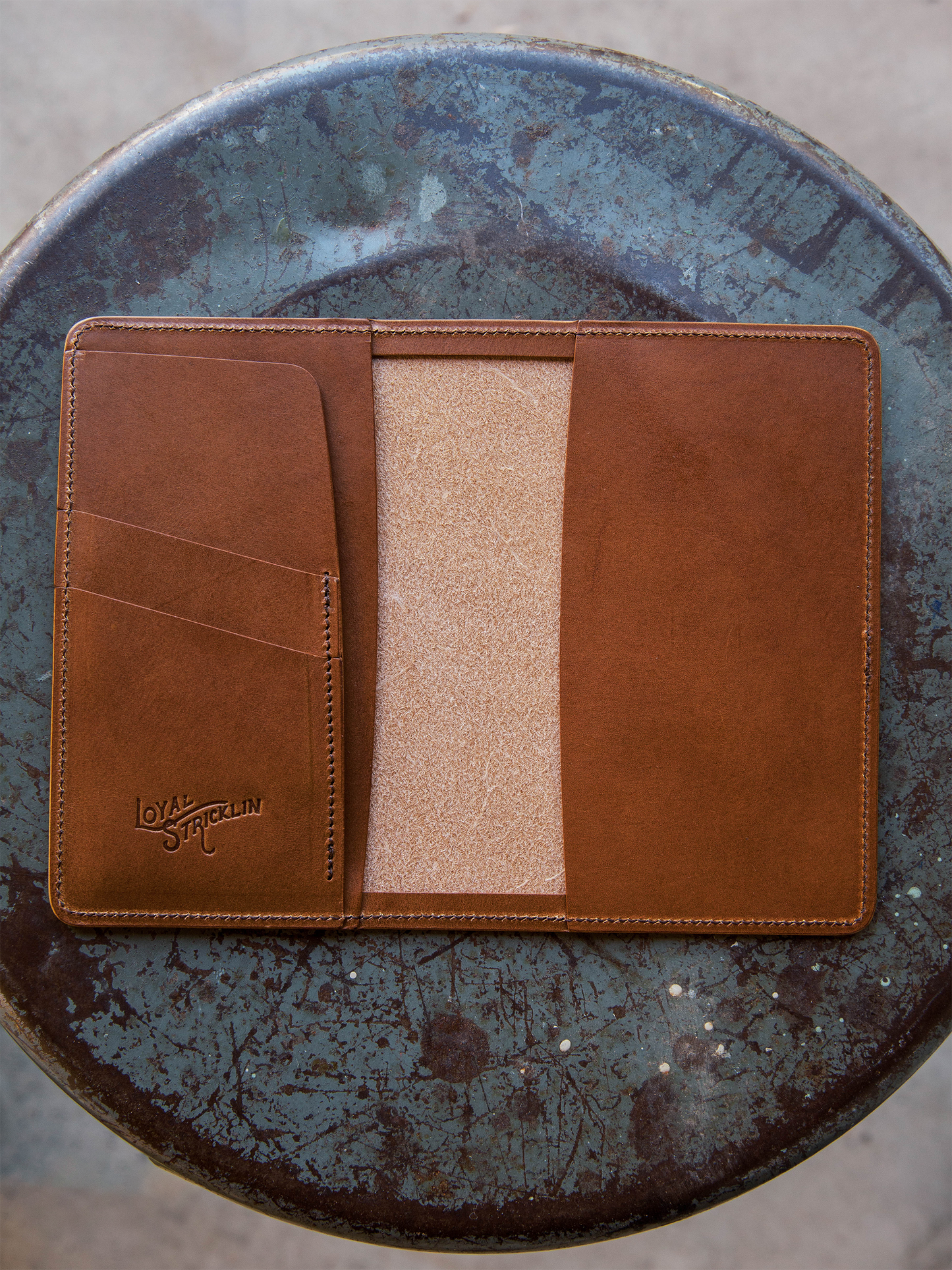 Brown leather wallet with a beige interior on a textured blue surface