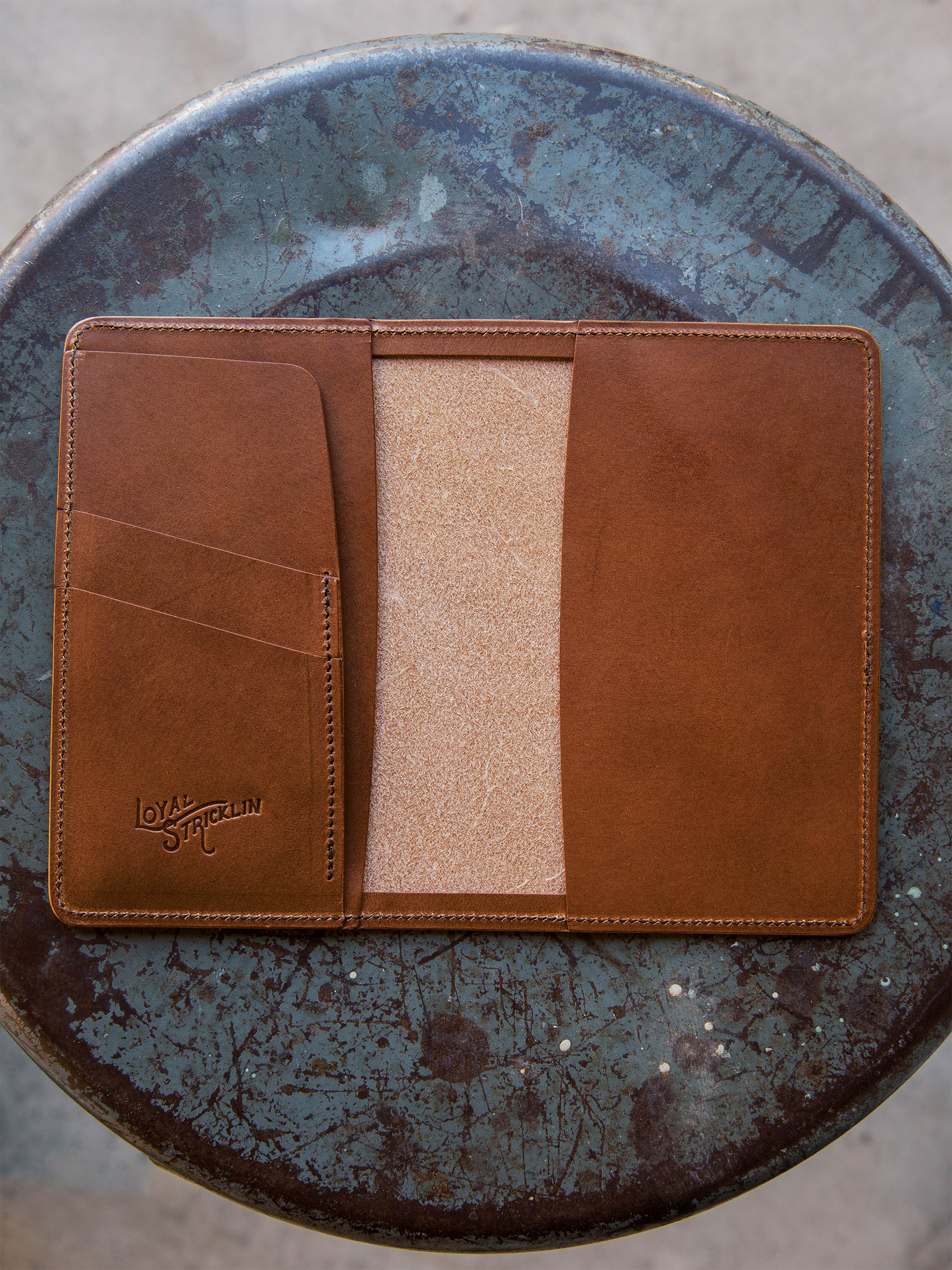 Brown leather wallet with a beige interior on a textured blue surface