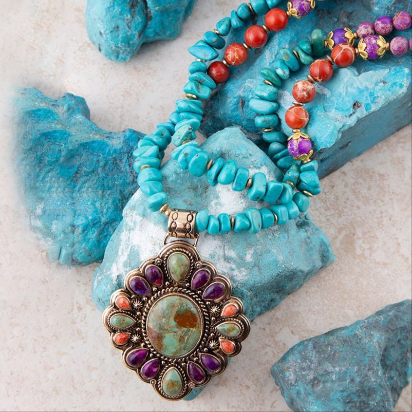 Turquoise beaded necklace with a decorative pendant on a textured surface